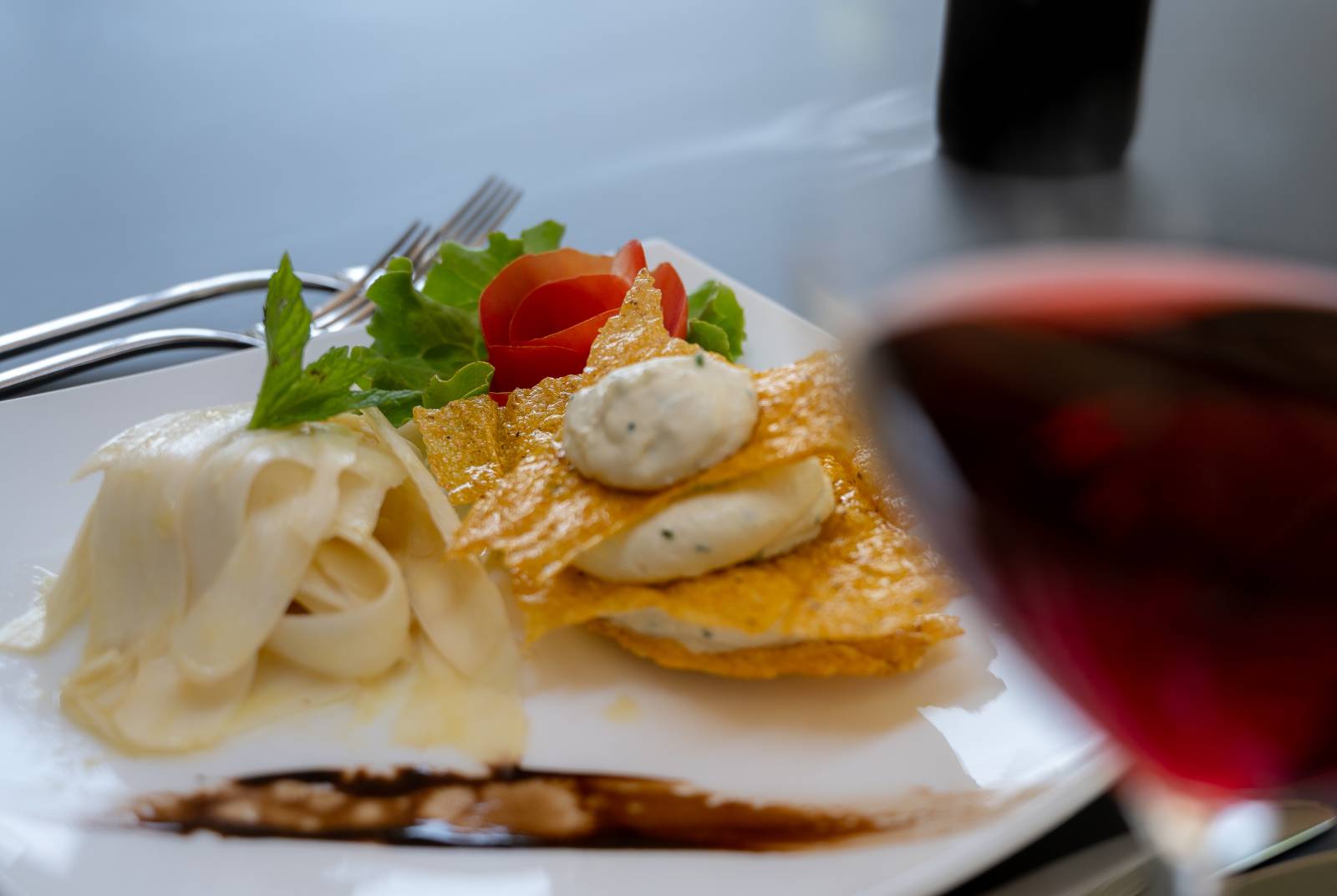 Delizioso antipasto con crema di formaggio spalmabile alle erbe e un bicchiere di vino rosso