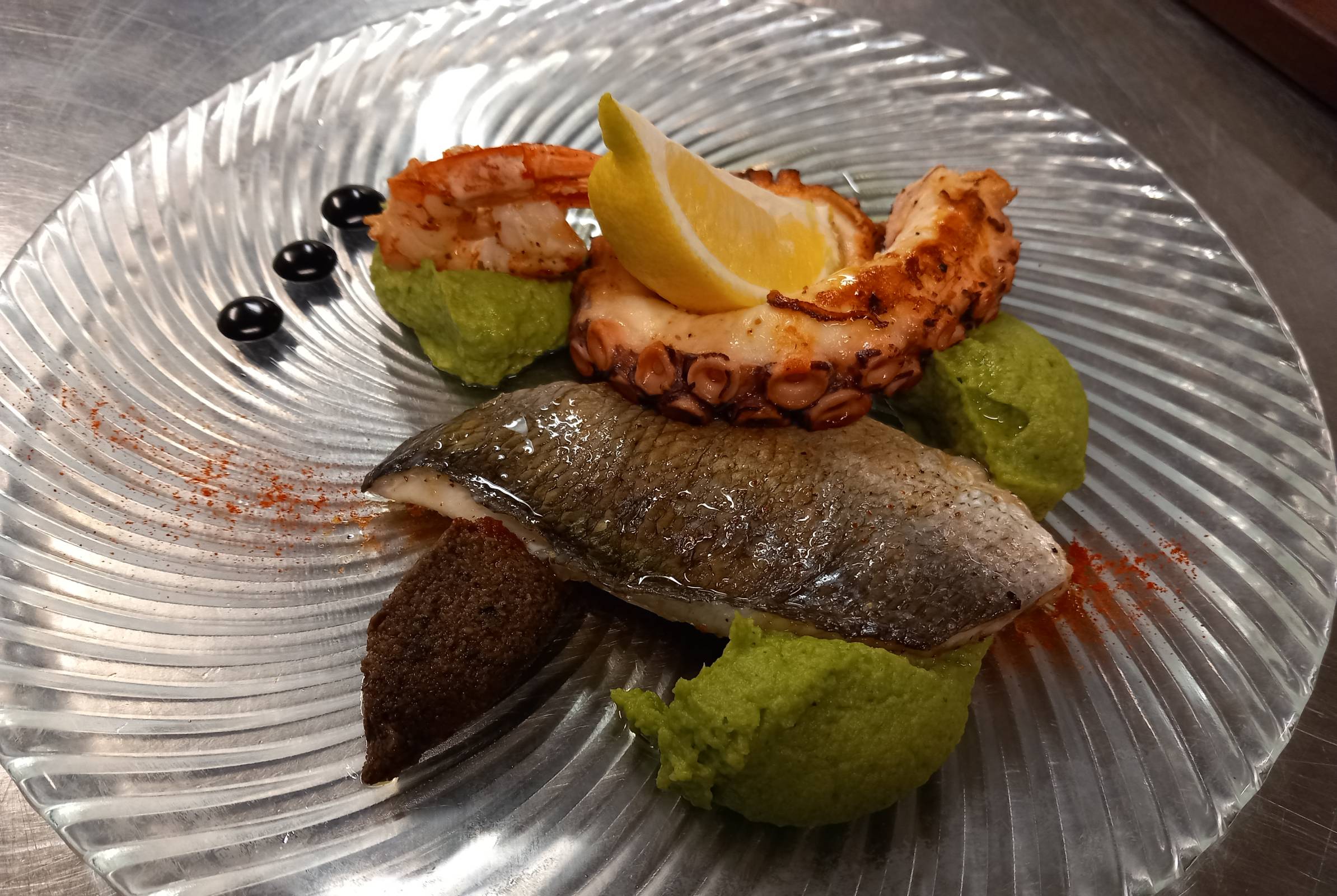 Delizioso piatto di pesce con pesto, polpo alla griglia e olive